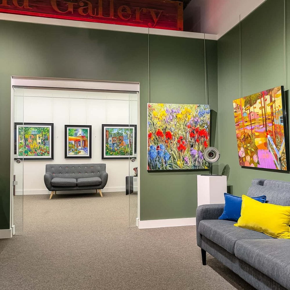 Modern office interior with colorful artwork on walls and a gray sofa.